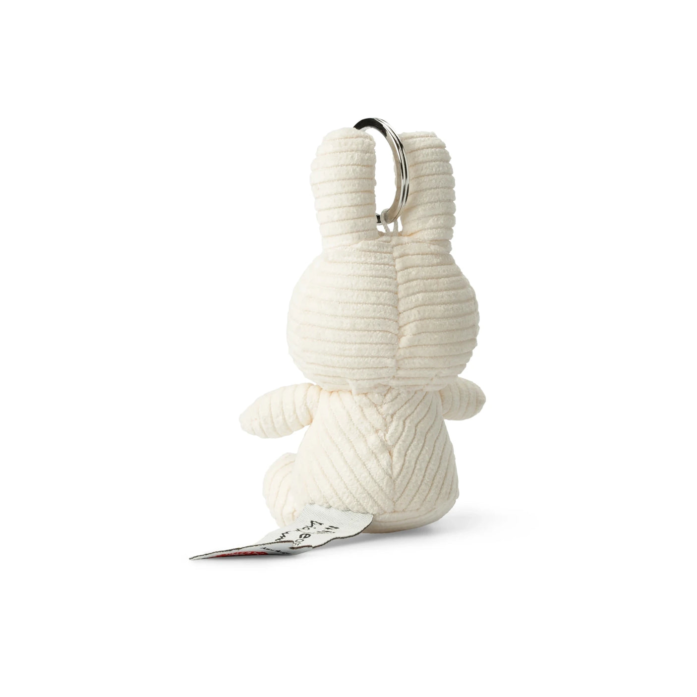 A plush Miffy Keychain Corduroy 10cm - Off-white, resembling a small bunny seen from the back with ribbed texture, eco-friendly design, and an attached paper tag.