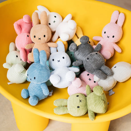 A collection of Miffy Bunny Plush Corduroy toys in ice blue, each measuring 23cm and crafted from recycled polyester, rests in a yellow container.