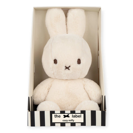 The Cozy Miffy Plush & Gift Box Cream - 23cm is a plush white bunny toy with long ears and a small face, nestled in a striped gift box. Made by the brand Miffy, it features super soft fabric.