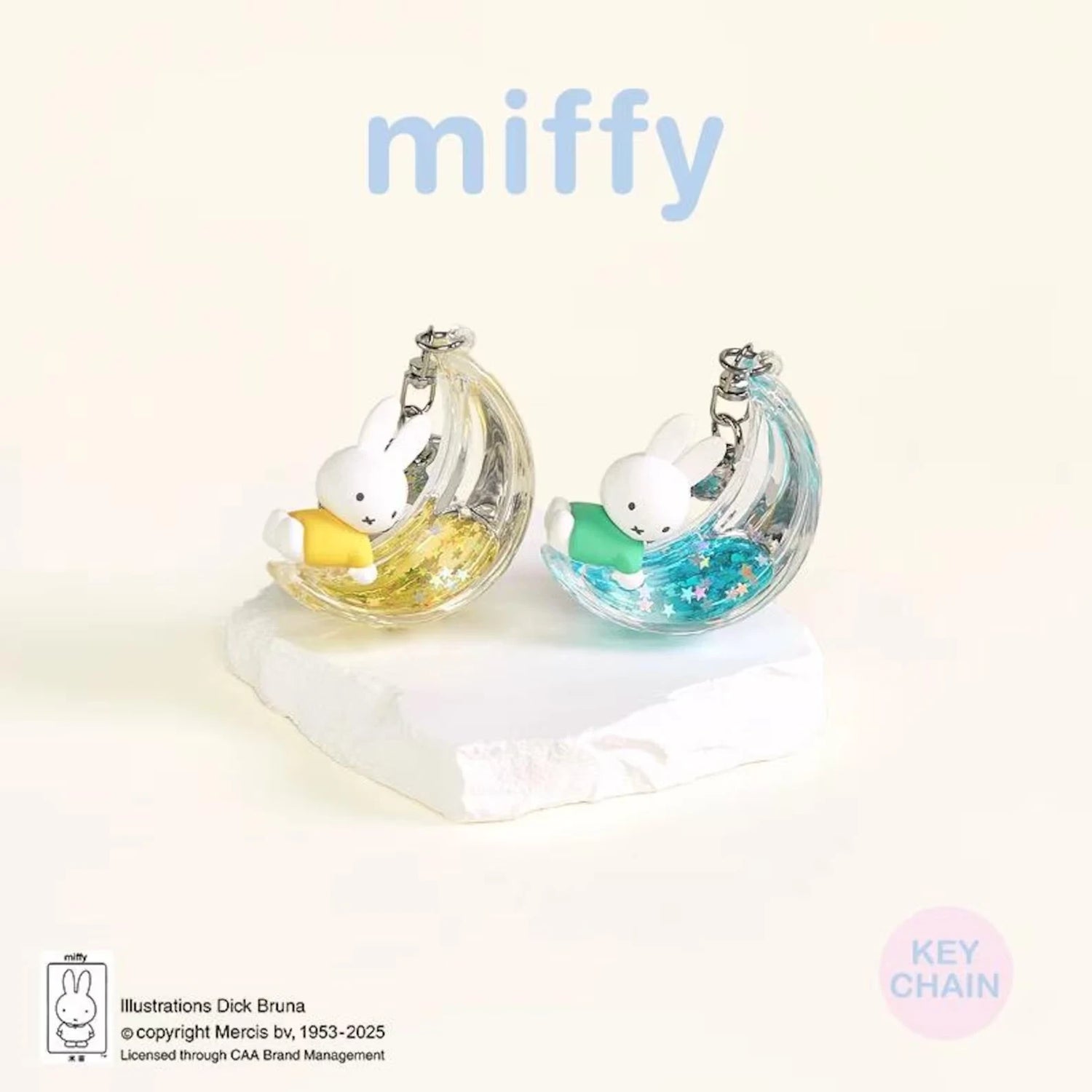 Two rabbit moon keychains with iridescent silver shells and pastel yellow and blue charms