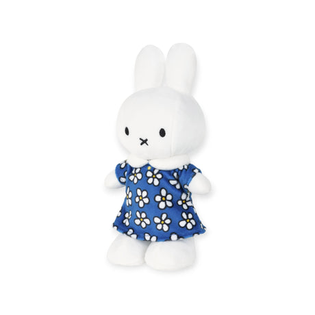 The Miffy Flower Dress Plush 23cm - Limited Edition celebrates 70 years with a white rabbit in a blue dress adorned with white flowers, standing upright against a plain background.