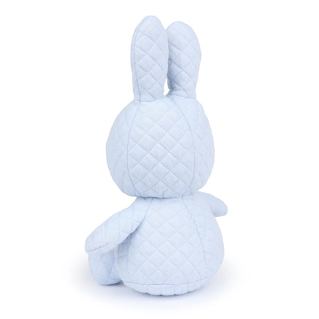 The Miffy Quilted Plush Gift Box - Blue 23cm, an environmentally conscious toy in a soft blue hue, bears a resemblance to the cherished Miffy Bunny and is depicted from behind, highlighting its ears, head, and body.