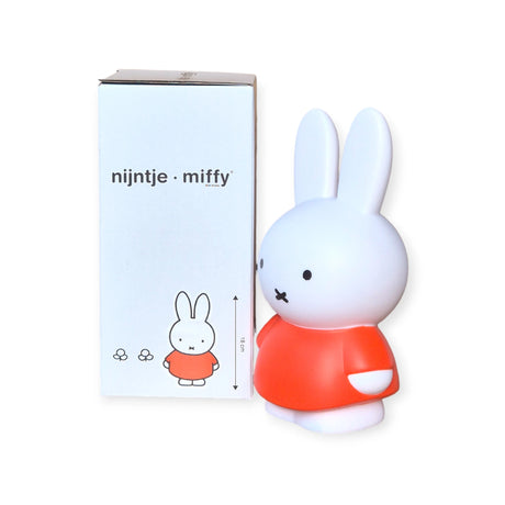 A Miffy Bunny adds a stylish accent to your home decor, sitting elegantly next to its packaging box. The red money box, standing 18cm tall, showcases a white bunny in a charming red outfit, effortlessly blending charm and whimsy with functionality.