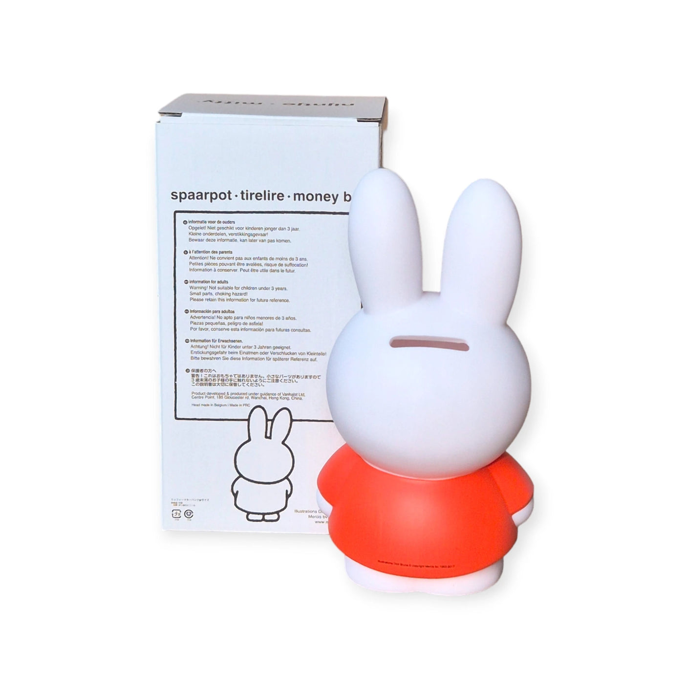 The Miffy Bunny - Red Money Box 18cm, by the brand Miffy, is a chic addition to any room. It showcases a white rabbit wearing a red shirt, making it an ideal decorative piece for your home. It stands elegantly in front of its packaging box decorated with multilingual text.