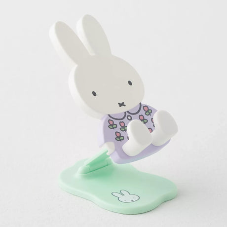 Pastel Miffy phone and tablet stand in purple floral dress sitting on mint green base with bunny face illustration on white background