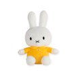 A gentle Miffy Plush Classic Yellow toy rabbit, featuring long ears and adorned in a yellow shirt, rests serenely against a plain white backdrop.