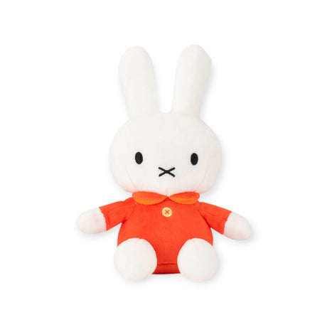 A soft and cuddly white plush bunny with long ears, dressed in a classic red outfit featuring a collar and button, this adorable Miffy Plush Classic Red - 20cm gently leans against a plain backdrop.