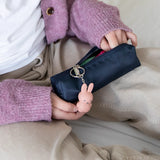 A child holds a navy blue pencil case embellished with a Miffy Keychain - Powder, adding a modern twist to its look.