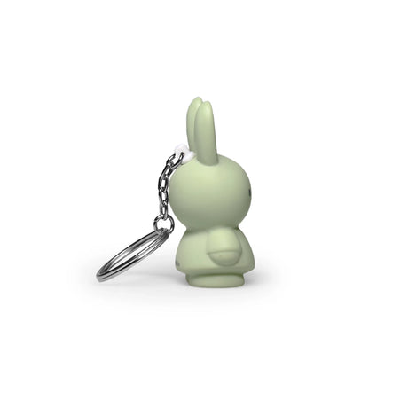 Side view of a small powder-colored rabbit-shaped keychain with a silver chain on a white background, offering a modern twist on the classic Miffy Keychain from the Miffy brand.