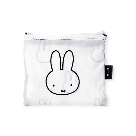 The Miffy Reusable Shopping Bag showcases a minimalist cartoon rabbit face in a black outline on a white pouch, complemented by an "atelier" labeled black tag for added elegance.