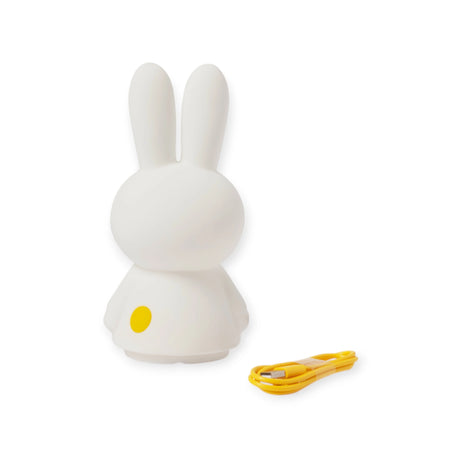 Introducing the Miffy Shines - Night Light (22cm) by Miffy, a delightful white rabbit-shaped lamp with long ears. It offers touch-sensitive dimming and includes a yellow button on the back for simple operation. This rechargeable lamp comes with a yellow USB cable, making it ideal for creating a cozy ambiance.