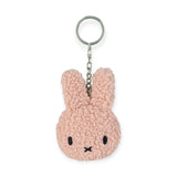 The Miffy Keychain Tiny Teddy Plush - Terry, by Miffy, is a pink keychain shaped like a rabbit and crafted from eco-friendly terry plush. It features round ears, simple black stitched details, and is attached to a silver keyring.