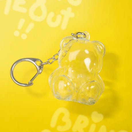 Transparent bear-shaped keychain with metal ring and clasp on bright yellow background with white text