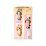 The Mofusand Premium - 8cm Adjustable Cat Blind Box showcases three charming cat figures donning various animal costumes against a pink backdrop adorned with paw prints, suitable for ages 8 and up.