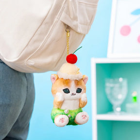 Plush keychain with gold chain, red cherry topper, cream cat with green shorts