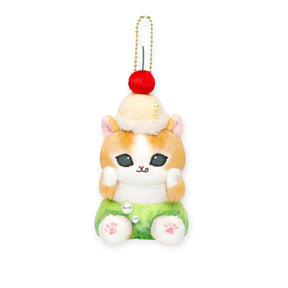 Front view plush keychain with gold chain, red cherry pom, cream cat in green shorts