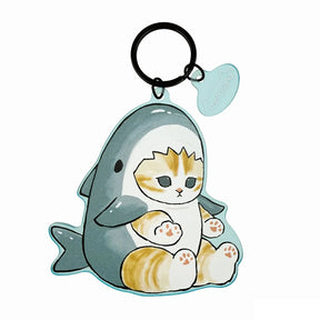 The Mofusand Shark Keychain by Mofusand features a translucent acrylic charm of a cat in a shark costume, complete with a black key ring and attached blue heart-shaped tag.