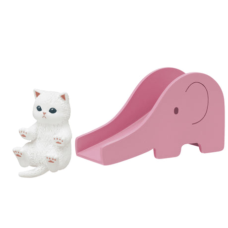 A miniature white cat figurine, similar to a discovery from the Mofusand Premium Blind Box - Cats on Slides collection, is positioned next to a pink slide shaped like an elephant.