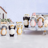 Displayed on a marble surface are seven small, charming animal-themed figurines, featuring characters like a panda, tiger, and rabbit. Among them is an endearing Mofusand Premium - 8cm Adjustable Cat from the blind box collection by Mofusand, adding an element of surprise and whimsy to the scene.