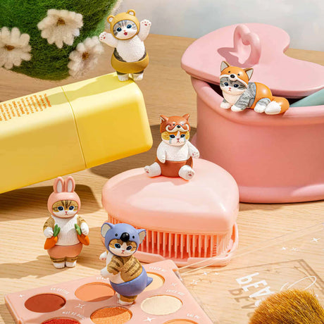 Charming animal figures from the Mofusand Premium - Nyanpantsu Blind Box, featuring adorable costumes, are displayed alongside makeup and skincare products on a wooden surface. Collect them all to add a delightful touch to your beauty space!