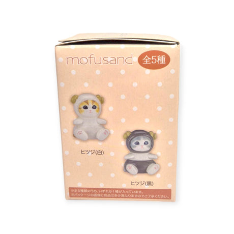 The Mofusand Mini Figure Blind Box - Vol 4 (Orange) showcases Mofusand branding, adorned with illustrations of two plush toys—a white one with yellow ears and a black one with green ears. The charming light pink background with polka dots makes this blind box ideal for fans eager to unveil which costumed kitty it holds inside.