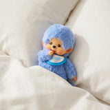 Blue plush doll with hooded hat and blue bib, posed on soft fabric