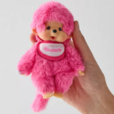 Monchhichi berry pink plush doll close-up, hood and logo scarf, held in hand
