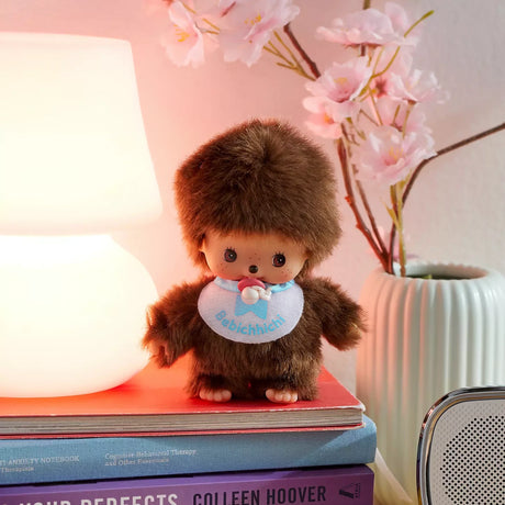 Brown fur plush doll with blue bib and pacifier, standing on books