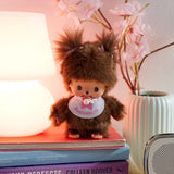 Brown plush doll standing upright, wearing a white bib with pink bow