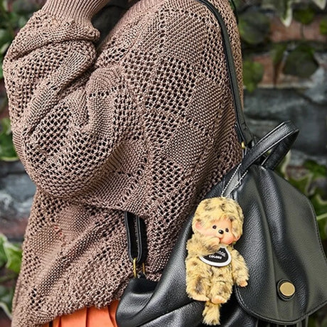 Leopard-pattern plush bag charm on a black handbag, with beaded chain