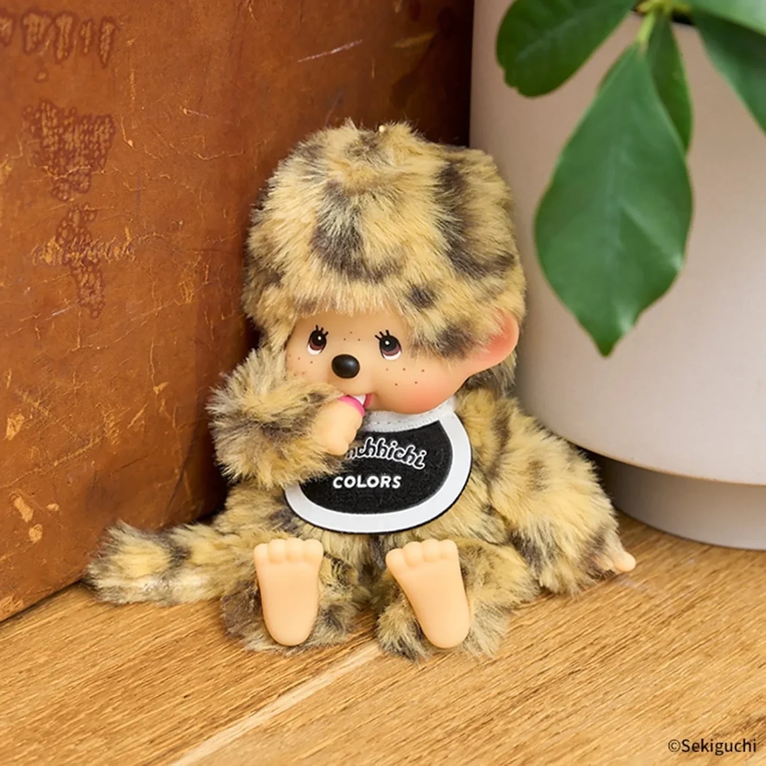 Leopard-pattern plush bag charm with beaded chain and round “Monchhichi COLORS” badge