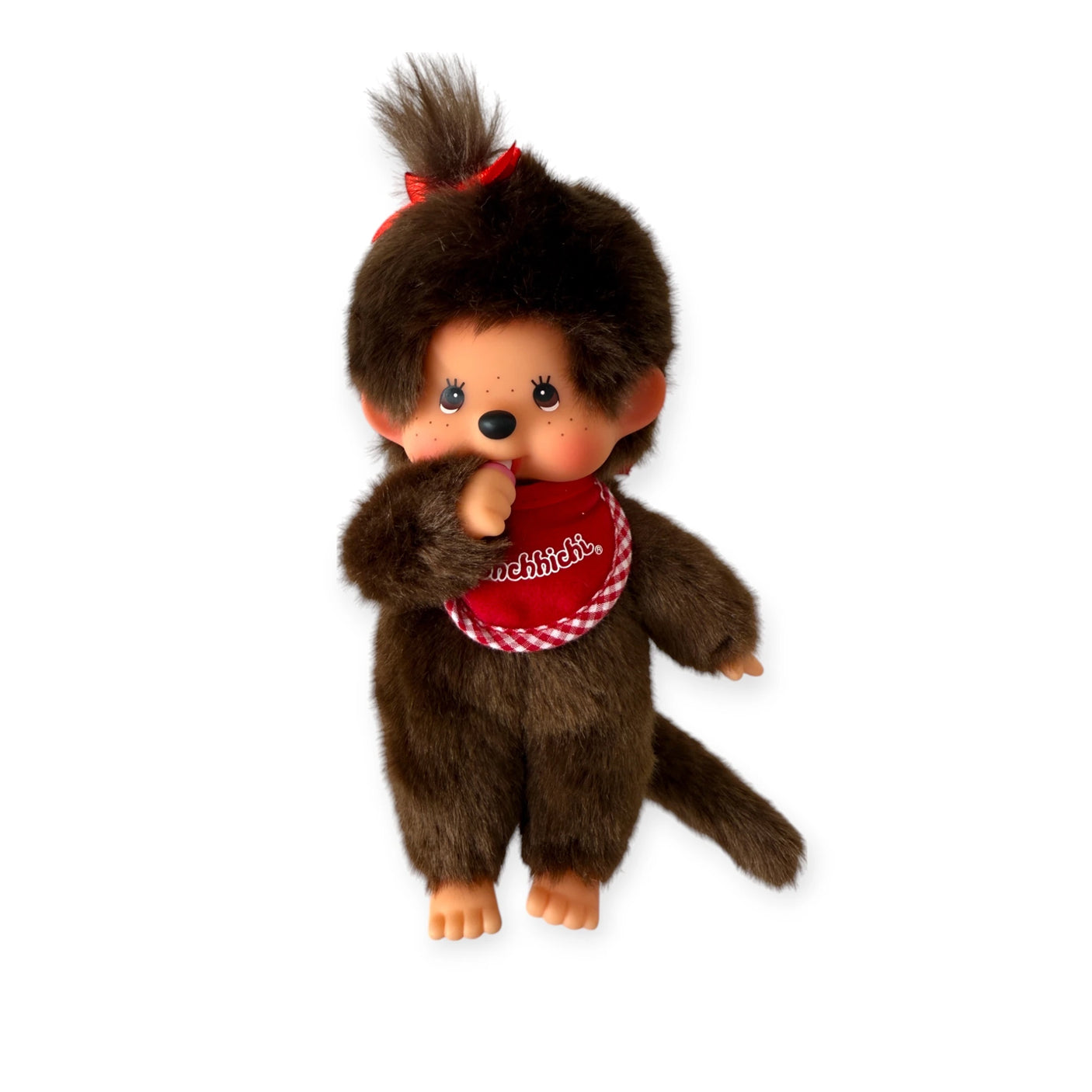 Introducing the Monchhichi Plush Doll - Twin Girl by Monchhichi, featuring brown fur, a red bib, and a charming hair bow. This collectible vintage plush doll is renowned for its adorable thumb-sucking pose, making it an endearing addition to any collection.