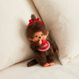 Monchhichi plush doll, brown fur, red bow and red checked dress, sitting