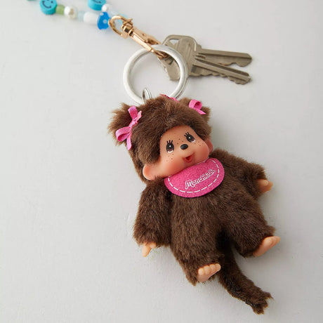 Dark brown plush girl keychain charm with pink bows and round pink badge