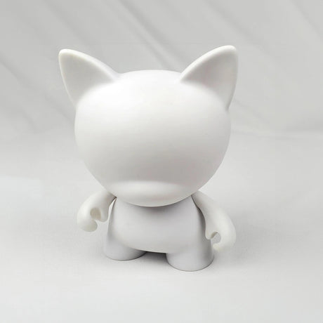 Introducing the Kidrobot Munnyworld - DIY Personalised Pop Vinyl mini figure, this plain white humanoid figurine with cat ears stands ready on a light surface, inviting creativity with its absence of facial features or distinct markings. Ideal for enthusiasts who enjoy crafting their own unique vinyl figures.