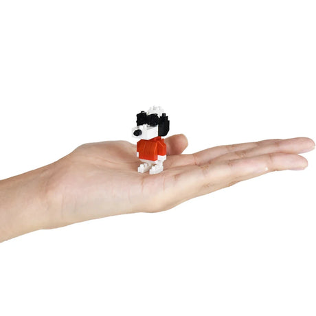 A small figure from the Nanoblock Peanuts Blind Bag - Vol. 3 rests on an open palm, encapsulating the charm of Snoopy, the beloved character.