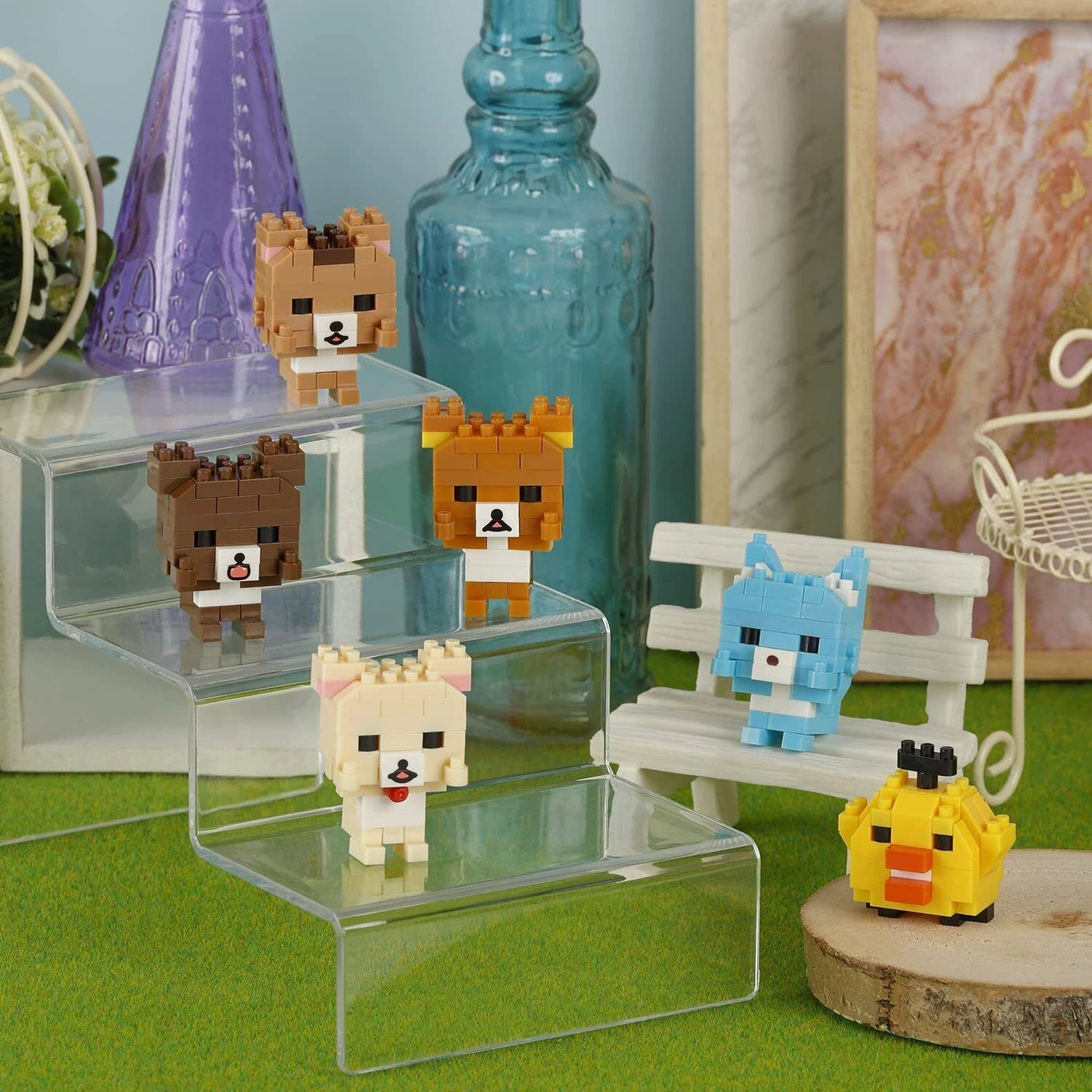 Explore the delightful Nanoblock Rilakkuma Blind Bag - Vol. 3 collection, showcasing six cute dog and duck brick figures, artistically displayed on clear steps and a bench. Enhancing this scene are decorative bottles and frames set against a green backdrop. Enjoy the thrill of blind bags as you aim to collect all six designs in this charming series by Nanoblock!