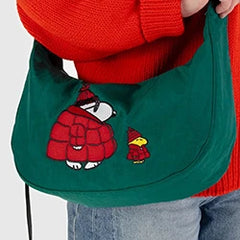 Person holding a green bag with embroidered characters wearing red winter clothes.