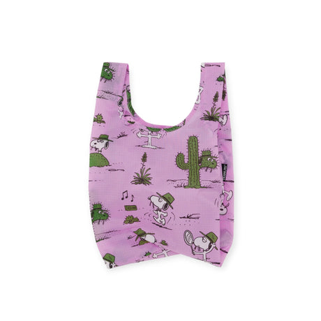 A pink Baby Baggu Peanuts - Snoopy Spike reusable shopping bag by Baggu, featuring cartoon dogs with hats set against a backdrop of cacti and other desert elements.