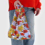 A person holding a Baby Baggu Peanuts - Floral Snoopy by Baggu, crafted from recycled nylon.