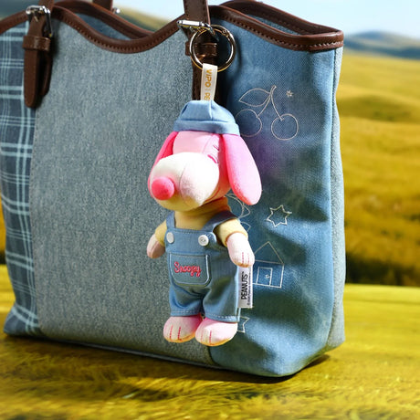 Colorful plush dog keychain with hang tag attached to light blue denim bag