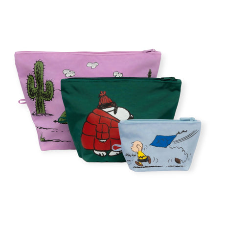 The Peanuts x Baggu Go Pouch Set by Baggu includes three vibrant zipper pouches adorned with Peanuts-style illustrations: a pink pouch featuring a cactus, a green pouch depicting Snoopy bundled up, and a light blue pouch with Woodstock flying a kite.