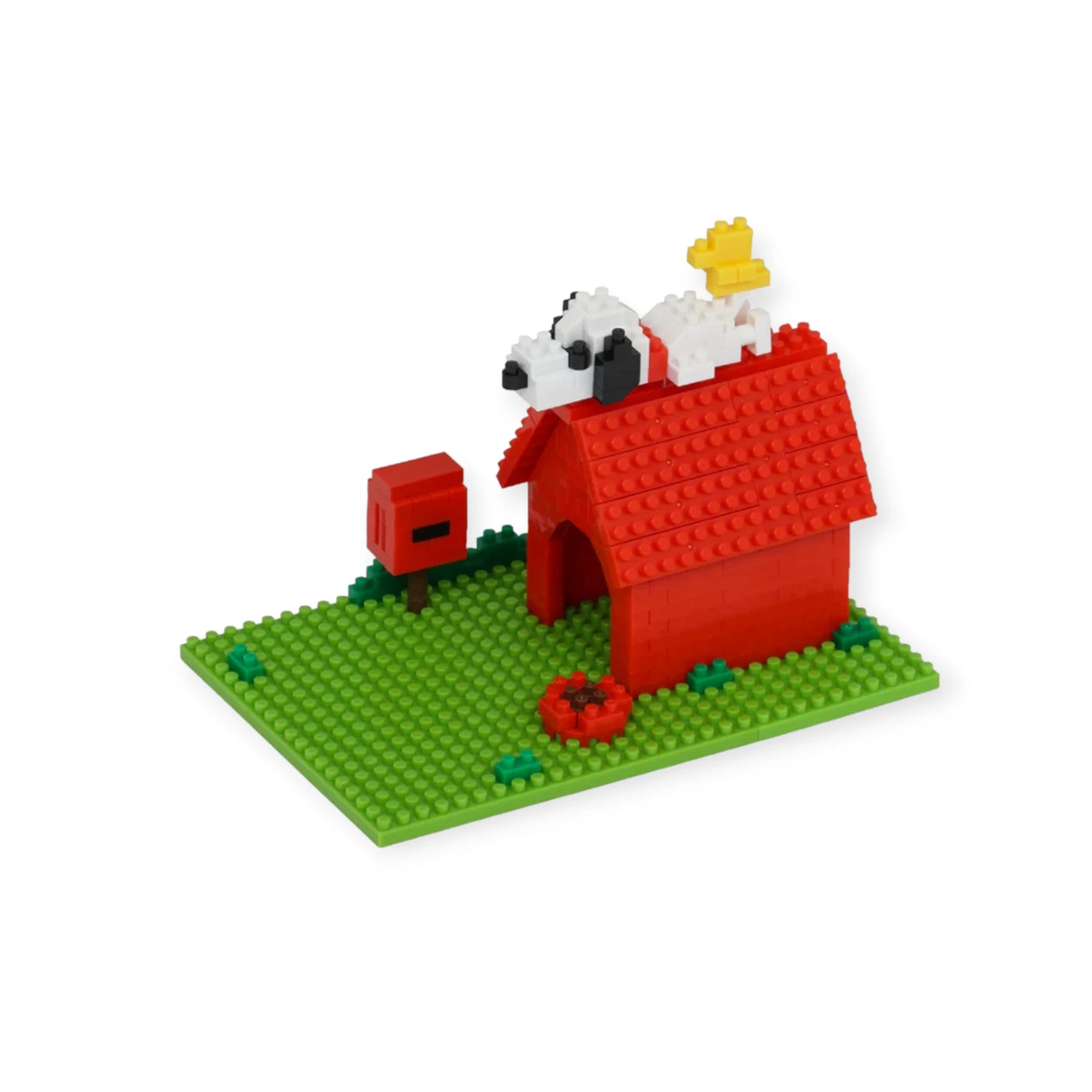 The Nanoblock Peanuts - Snoopy House Set from Nanoblock beautifully captures a Lego-style model with a red doghouse on a green baseplate. It features a white dog figure reminiscent of the iconic Snoopy, topped by a small yellow bird. A red mailbox and dish complete this charming scene rooted in Peanuts history.