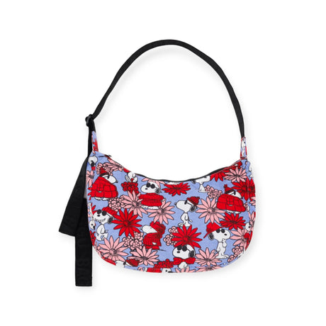 Introducing the Medium Crescent Bag Floral Snoopy by Baggu, a vibrant shoulder bag from the exclusive Baggu x Peanuts collaboration. This stylish accessory is adorned with a colorful floral and cartoon dog pattern, featuring a sleek black strap and tassel detail. It's crafted from recycled nylon for an eco-friendly touch.