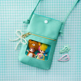 Turquoise mini pouch with clear pocket holding two blind box character dolls