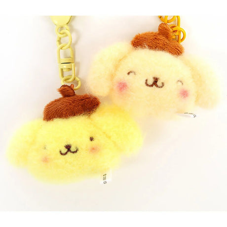 Two mini plush keychains close-up: yellow faces with brown caps, yellow chain links