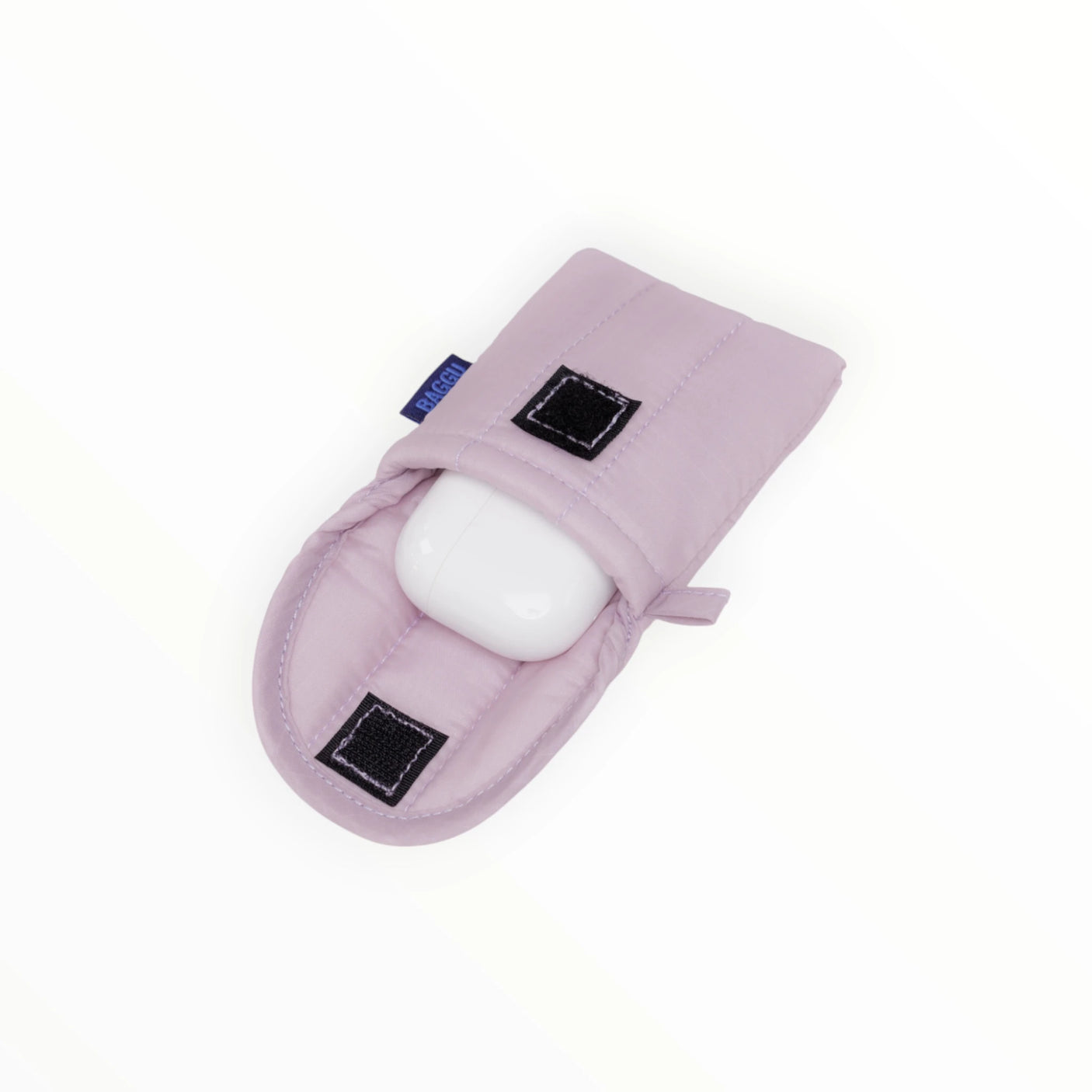 A single white egg rests in a Baggu Puffy Earbuds Case in dusty pink, featuring quilted padding and secured by two black Velcro straps, set against a plain white background.