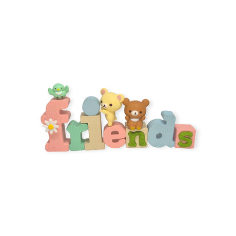 Experience the vibrant assortment of the Rilakkuma Words Blind Box by Re-Ment, showcasing colorful 3D letters spelling "friends," each accompanied by delightful small toys like a green bird, a yellow bear, and an adorable Rilakkuma, all elegantly displayed as cherished collectibles.