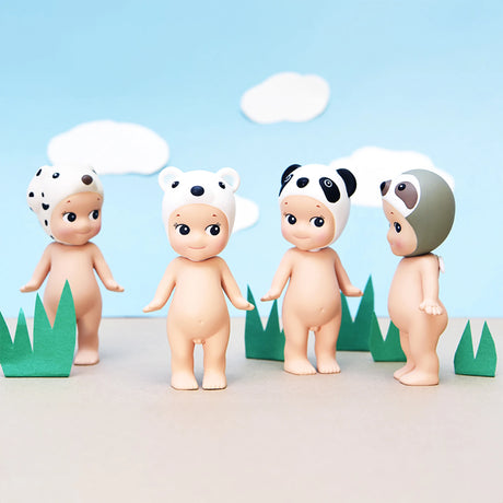 Four collectibles from the Sonny Angel Animal Version 1 Series stand on a paper surface, sporting adorable animal hats. Set against a backdrop of grass and clouds, these figurines are a charming part of the Sonny Angel collection.