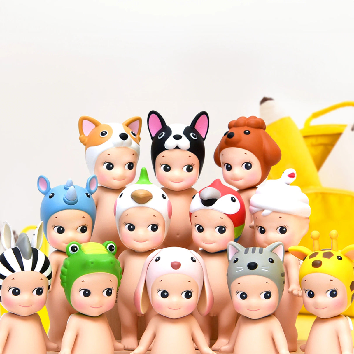 A collection of Sonny Angel Animal Version 3 Series figures, from the Sonny Angel brand, dressed in a variety of animal hats, stands charmingly before an array of yellow items against a pristine white background. These delightful blind box treasures captivate with their whimsical appeal.